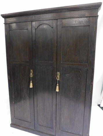 A 20thC oak stained hall wardrobe, with moulded cornice raised above a central panel flanked by two doors revealing a plain interior, on block base, 192cm high, 138cm wide, 25cm deep.