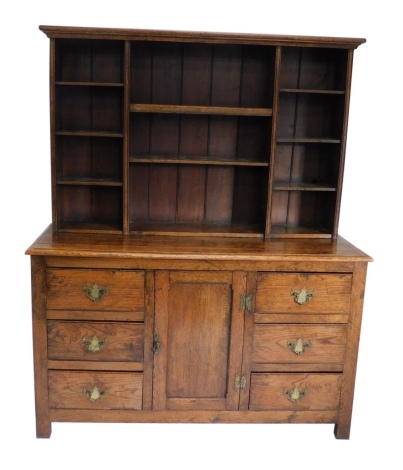 An 18thC style oak dresser, the upper section set with an arrangement of open shelves, the base with a single cupboard flanked by six drawers, on stiles, 180cm high, 146cm wide, 53cm deep.