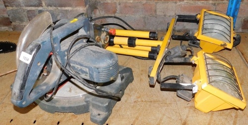 An electric circular saw, together with a pair of electric Floodlights United lights, supported on a single tripod base.