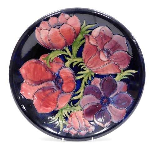 A Moorcroft Anemone pattern pottery charger, blue ground, impressed and painted marks, 35cm diameter.