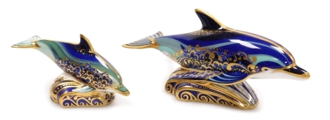 Two Royal Crown Derby porcelain paperweights, comprising Bottlenose Dolphin, 18cm wide, and Baby Bottlenose Dolphin, 12cm wide, both with red printed marks and gold stoppers.