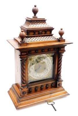 A late 19thC mahogany cased mantel clock, the brass Arabic numeral face with silvered chapter ring, foliate spandrels and eight day movement, the case of ornate form, with turned finials, stepped roof top, turned columns on a stepped base, with key and pe