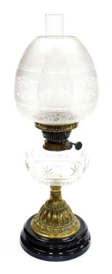 A late 19thC cut glass and brass oil lamp, with a clear and opaque floral etched shade, clear cut glass central reservoir, raised on an embossed brass column, on a painted socle base, 57cm high.