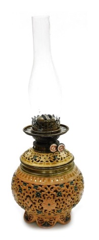 An early 20thC pottery oil lamp, with a clear glass chimney, the base with reticulated floral decoration, blues and pinks, lacking shade, 50cm high overall.