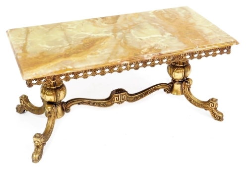 A gilt metal coffee table, the rectangular golden onyx top with a moulded edge above a pierced frieze, on twin supports with splayed legs, 100cm wide.