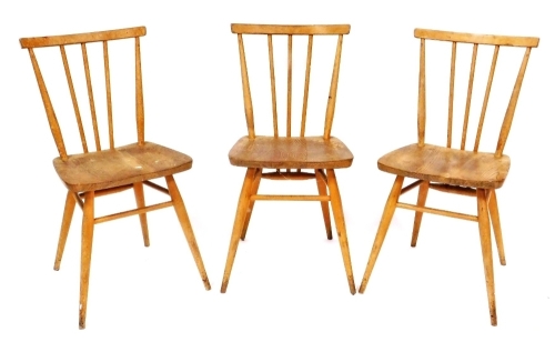 A set of three Ercol ash and elm stick back chairs, each with a solid seat on turned legs with stretchers, impressed mark to underside.