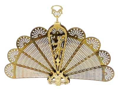 A brass fan shaped spark guard, cast with figures, scrolls, etc., with a pierced handle, 84cm high.