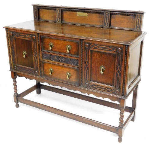 An early 20thC oak dresser, the top with a raised carved back, above a moulded edge, the base with two central doors, flanked by two carved panelled doors, raised on turned legs united by a box shaped stretcher, the back panel bearing brass presentation p