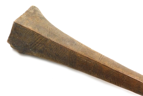 A 19thC Tongan Apa Apai war club, of dense hardwood, the tapering diamond shaped head carved with panels of geometric bands of chevrons, continuing with a plain cylindrical shaft, terminating in a triangular grip with suspension hole, 85cm wide. (AF)