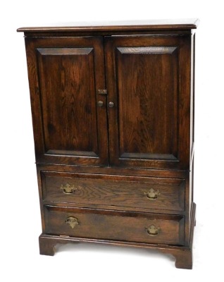 A Georgian style oak cupboard, with two panelled doors over a long drawer over a drop down long drawer, raised on bracket feet, originally for use as a television cabinet, back lacking, 117cm high, 80cm wide, 52.5cm deep.