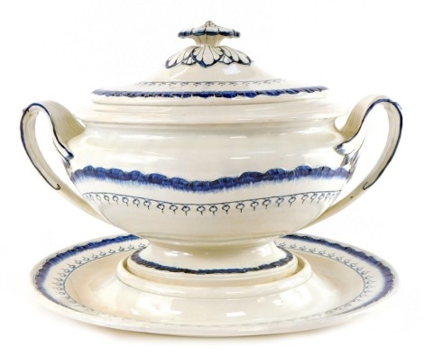 A Wedgwood early 19thC Cream Ware soup tureen cover and stand, painted in blue and white, with a floral finial and scrolling handles, impressed marks, 35cm wide.