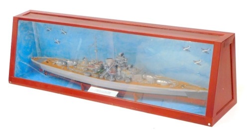 A wooden scale model of the German battleship Bismarck, mounted on a cradle, in a Perspex fronted wooden case, with painted backdrop, model 127cm wide, case 140cm wide.