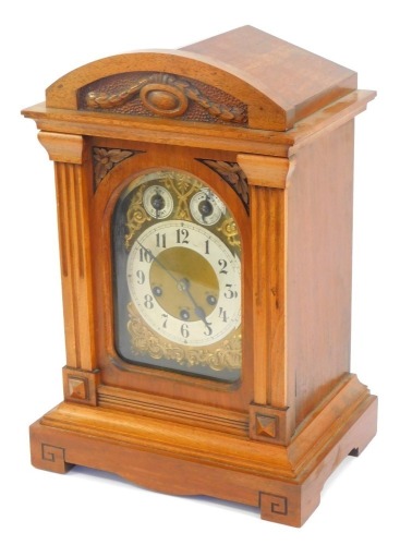 An early 20thC Junghans oak cased mantel clock, the arched brass dial with foliate scroll spandrels, silvered chapter ring bearing Arabic numerals, subsidiary chime silent and slow fast dials, eight day movement with coil and rod strike, with Westminster