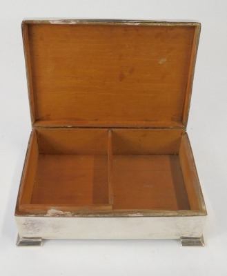 A George V silver cigarette box, with a shaped top, on out swept feet, bearing later engraving to reverse 'To My Friend BBH, Head Student N.T.C.D.J 1941-42 K.L.T', Birmingham 1911, with a wooden lined interior, 6cm high, 14cm wide, 15.99oz gross. - 2