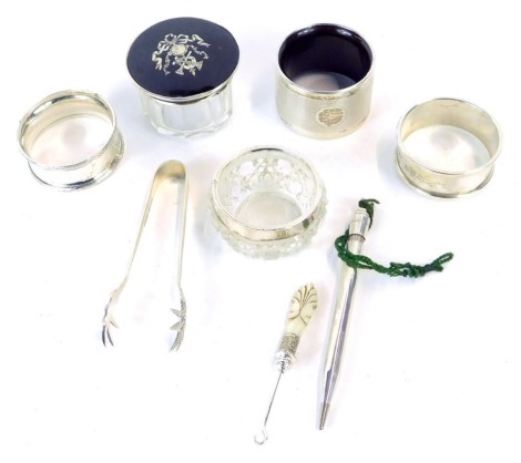 Silver trinkets and effects, comprising three silver napkin rings, one of engine turned design with vacant shield, one bearing initials MYHW, further with Neoclassical scroll border, a tortoiseshell and silver topped dressing table jar, silver rimmed salt