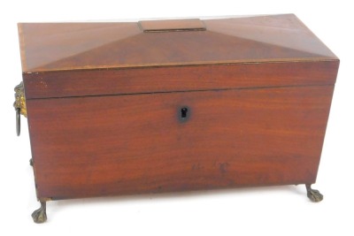 A late Regency mahogany sarcophagus form tea caddy, with brass lion's head and ring handles, the hinged lid opening to reveal a vacant interior, raised on ball and claw feet, 21cm wide.