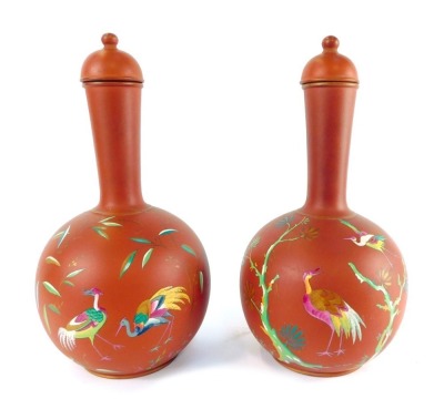 A pair of late 19thC terracotta bottles and lids, enamel decorated with exotic birds, number 9987, 30cm high.