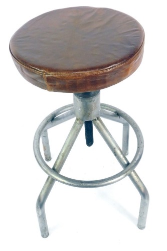 A mid century industrial tubular steel laboratory stool, with an adjustable circular tan leather seat, 62cm high.