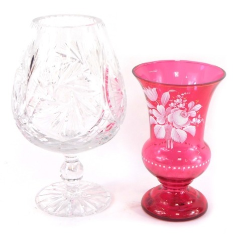 A Bohemian cut glass vase, the balloon shaped bowl raised on a single knopped stem over a circular foot, 28cm high, and a cranberry glass vase, over painted in white with a spray of flowers, 21cm high. (AF)