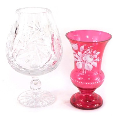 A Bohemian cut glass vase, the balloon shaped bowl raised on a single knopped stem over a circular foot, 28cm high, and a cranberry glass vase, over painted in white with a spray of flowers, 21cm high. (AF)