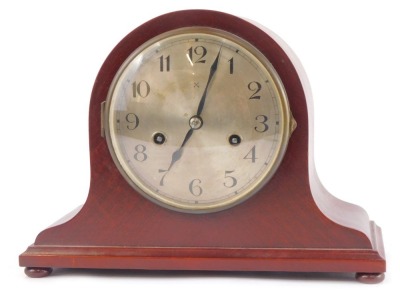 An early 20thC Hamburg American Clock Company mahogany cased mantel clock, circular silver dial bearing Arabic numerals, eight day movement with coil strike, the case of domed form, raised on bun feet, with pendulum and key, 28cm wide.