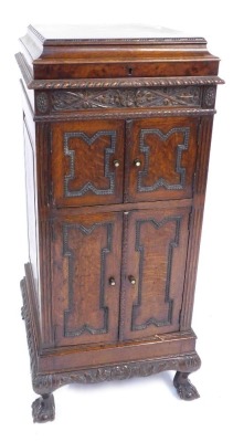 An early 20thC oak cased cabinet gramophone, with record played inset top, and two swing doors with ebonised handles, and a two cupboard base, with four shelves, on ball and claw feet, 21cm high, 51cm wide, 54cm deep.