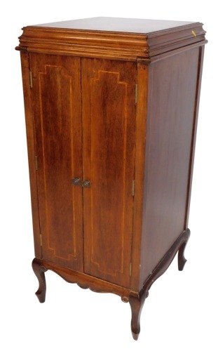 An Edwardian mahogany gramophone cabinet, lacking gramophone interior, with cross banding and a shaped hinged domed top, on splayed legs, 112cm high, 47cm wide, 51cm deep.