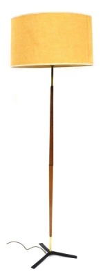 A 1960's teak and brass standard lamp, with an oatmeal coloured shade, raised on a cast iron tripod base, 156cm high. Keyword searches: Svend Aage Holm-Sorensen.