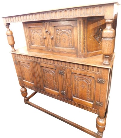 A 17thC style oak court cupboard, the rectangular raised top on supports, with two carved panel doors, above an arrangement of three drawers on block base with baluster legs, 147cm high, 235cm wide, 45cm deep.