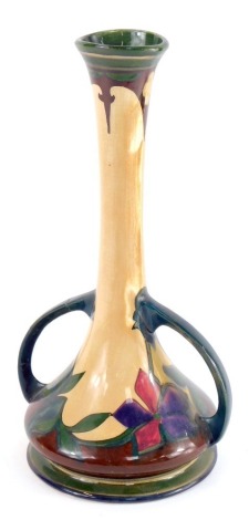 An early 20thC Art Nouveau Gouda pottery vase, of twin handled slender neck form, decorated with flowers, painted mark, 32cm high. (AF)