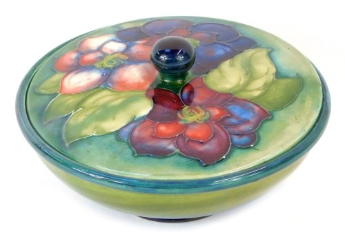 A Moorcroft pottery Clematis pattern bowl and cover, with a transitional blue to green ground, signed W Moorcroft, impressed marks, 16cm diameter.