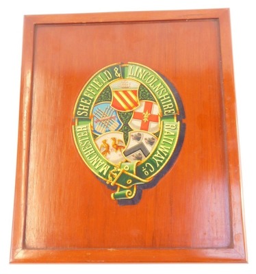 Railway interest, a mahogany panel printed with the Arms and Garter of the Manchester, Sheffield, and Lincolnshire Railway Company, 46cm x 30cm.