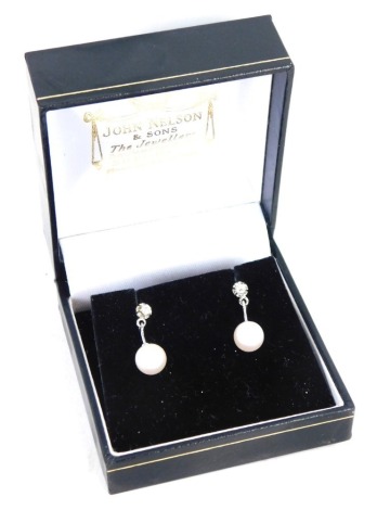 A pair of 18ct white gold cultured pearl and diamond drop earrings, each with a tiny diamond in four claw setting, with a 1cm drop on cultured pearl, on single pin back with butterfly backs, 2.8g all in, boxed.