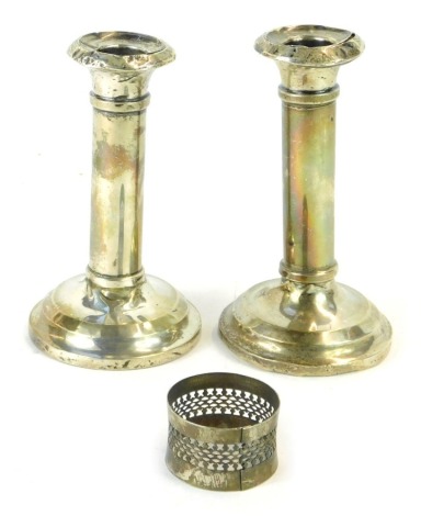 A pair of George V silver dwarf candlesticks, on loaded bases, Birmingham 1919, 14cm high, together with a silver napkin ring, 10.56oz all in.