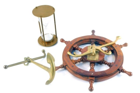 A wooden ship's wheel and brass coat stand, 32cm wide, brass model of an anchor, and a brass and glass sand timer, 15cm high. (3)