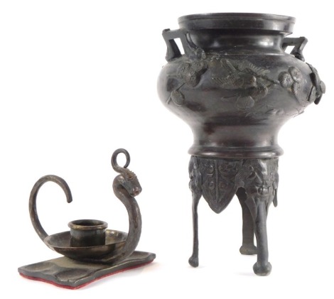 A Japanese Meiji bronze censer, of twin handled form cast to the body with birds and blossom, raised on mask and paw feet, 21cm high (AF), together with a cast iron candle holder, of scrolling serpent form raised on a rectangular base, 15cm wide.