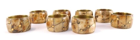 A set of eight late 20thC horn and brass inlaid napkin rings, each 4.5cm wide.