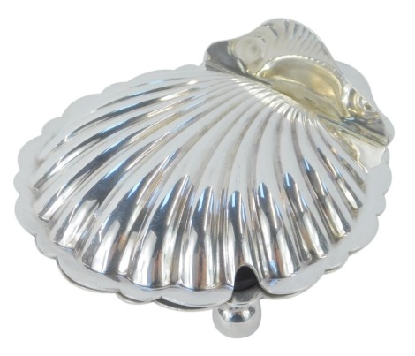 A Mappin and Webb silver plated butter dish, of scallop shell form, with a hinged lid opening to reveal a glass liner, raised on two ball front feet and a V shaped rear support, impressed number W27476, 13cm wide.