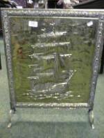 An embossed brass fire screen