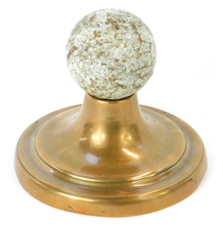 An early 20thC Bromford 15 PGA golf ball, raised on a turned copper stand.