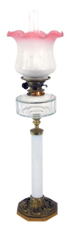 A early 20thC Hinks & Sons brass and glass oil lamp, on single column support with clear glass reservoir, on a foliate scroll embossed octagonal base, with chimney and floral decorated frosted to cranberry glass shade, 82cm high.