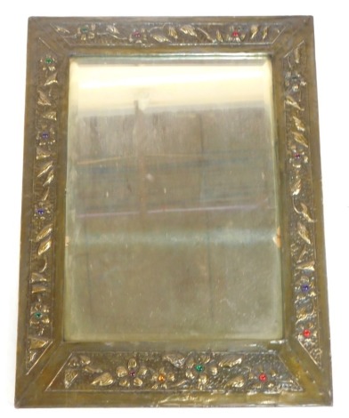 An early 20thC Arts & Crafts brass rectangular framed wall mirror, inset bevelled glass, the surround embossed with flowers, with jewelled glass flower heads, 47cm high, 35cm wide.