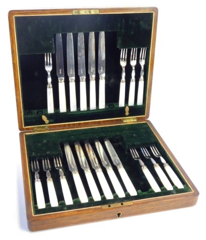 A part canteen of mother of pearl and stainless steel bladed fruit knives and forks, in a fitted oak box, with a green velvet interior, box 28.5cm wide.