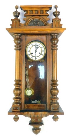 A late 19thC walnut cased Vienna wall clock, with a moulded top, Corinthian columns with white ceramic Roman numeric dial, and pendulum, 83cm high, with key.