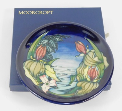 A Moorcroft Pottery plate decorated with pond flowers, against a blue background, painted and impressed marks, 26cm wide, boxed. - 3
