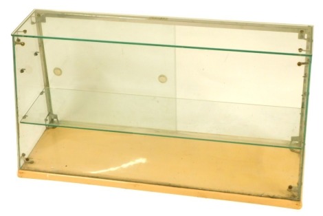 A 20thC table top glass shop display cabinet, with a sloped front and single shelf, on a pink plastic base, 46cm high, 90cm wide, 30cm deep.