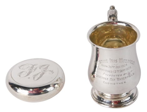 A George V silver mug, with bell shaped body, acanthus leaf handle and circular foot, engraved, Birmingham 1925, 9cm high, and a silver snuff box, with flush lid, initialled, 4.2oz. (2)