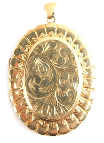 A 9ct gold oval locket, chased with scrolls, with an outer geometric border, with shaped top marked 375, 6cm high, 23g all in.