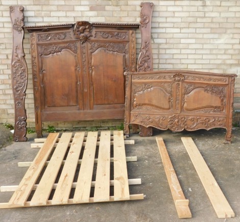 A Continental oak bed head and associated footboard, the elaborately carved head section with cartouche shaped moulded and raised panels, surrounded by scrolls, flowers, etc., centred with a shell, the footboard with similar decoration, 168cm high, 163cm 