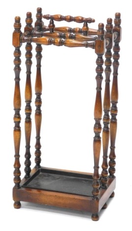 A mahogany umbrella stand, with turned supports and metal drip tray, 66cm high, 30cm wide.